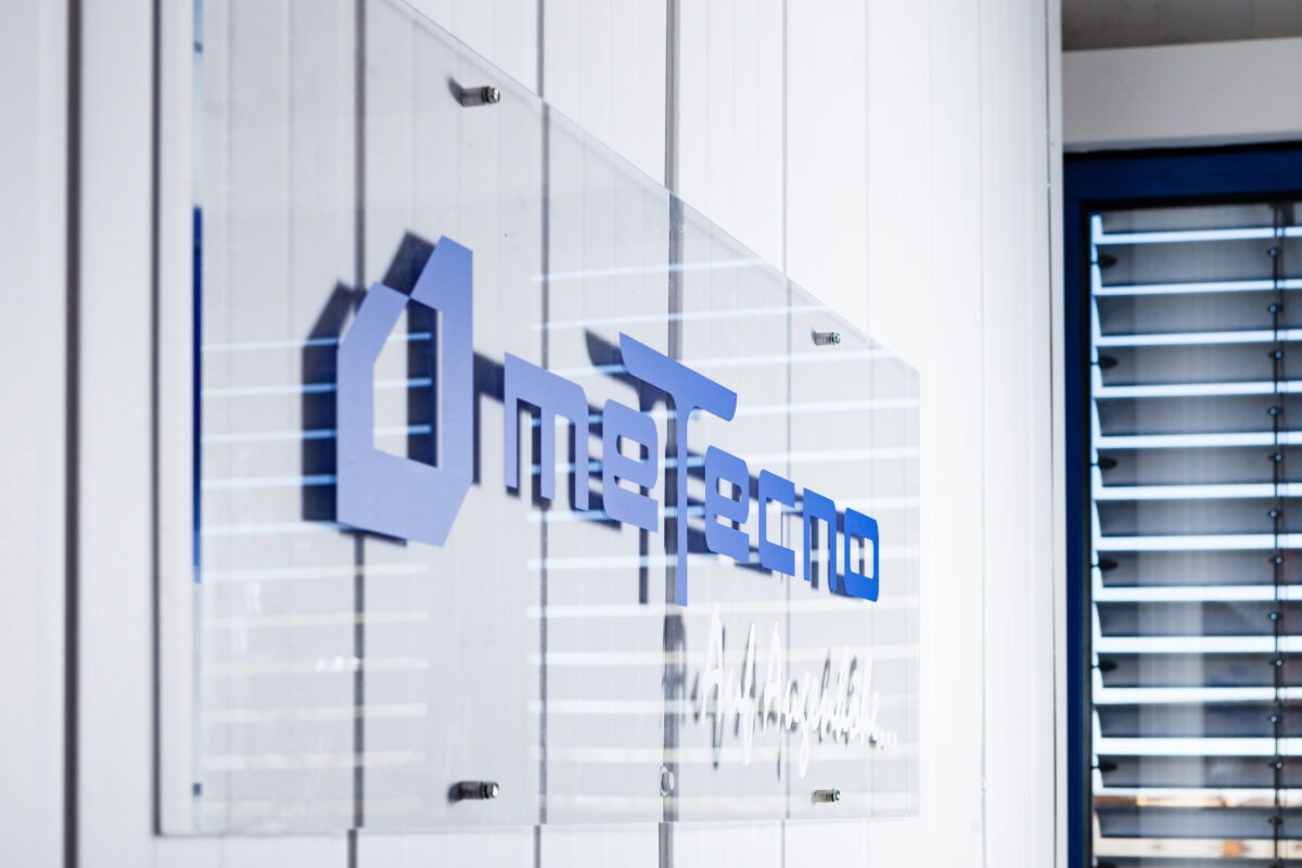 logo Metecno sur plaque fixée à un mur, représentant un fabricant de solutions isolantes et de panneaux métalliques pour bâtiments industriels.